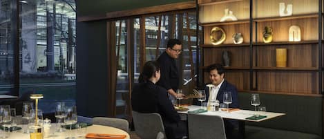 A modern dining area with a round table, chairs, and a waiter serving.