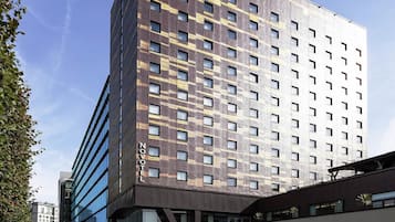 A modern hotel with a unique facade, multiple floors, and a prominent 'NOV' sign.
