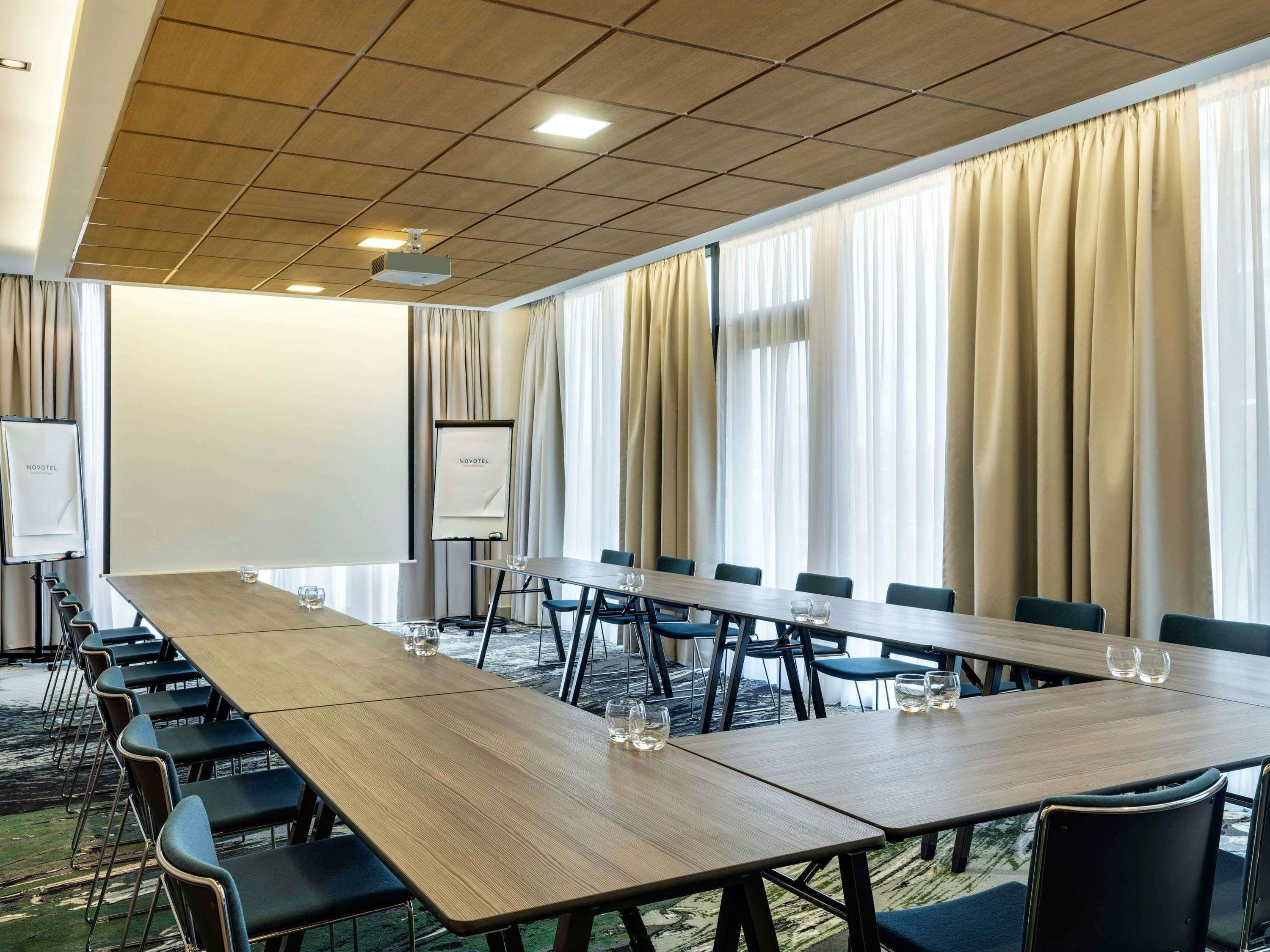 Ein Konferenzraum mit einem langen Tisch, Stühlen, einem Projektor und einer Tafel.