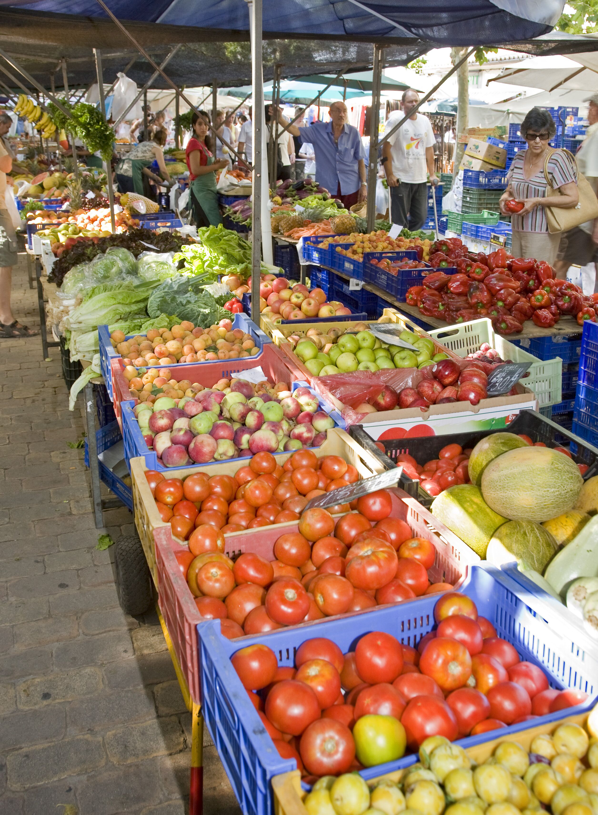 A market stall with various fruits and vegetables displayed in crates.