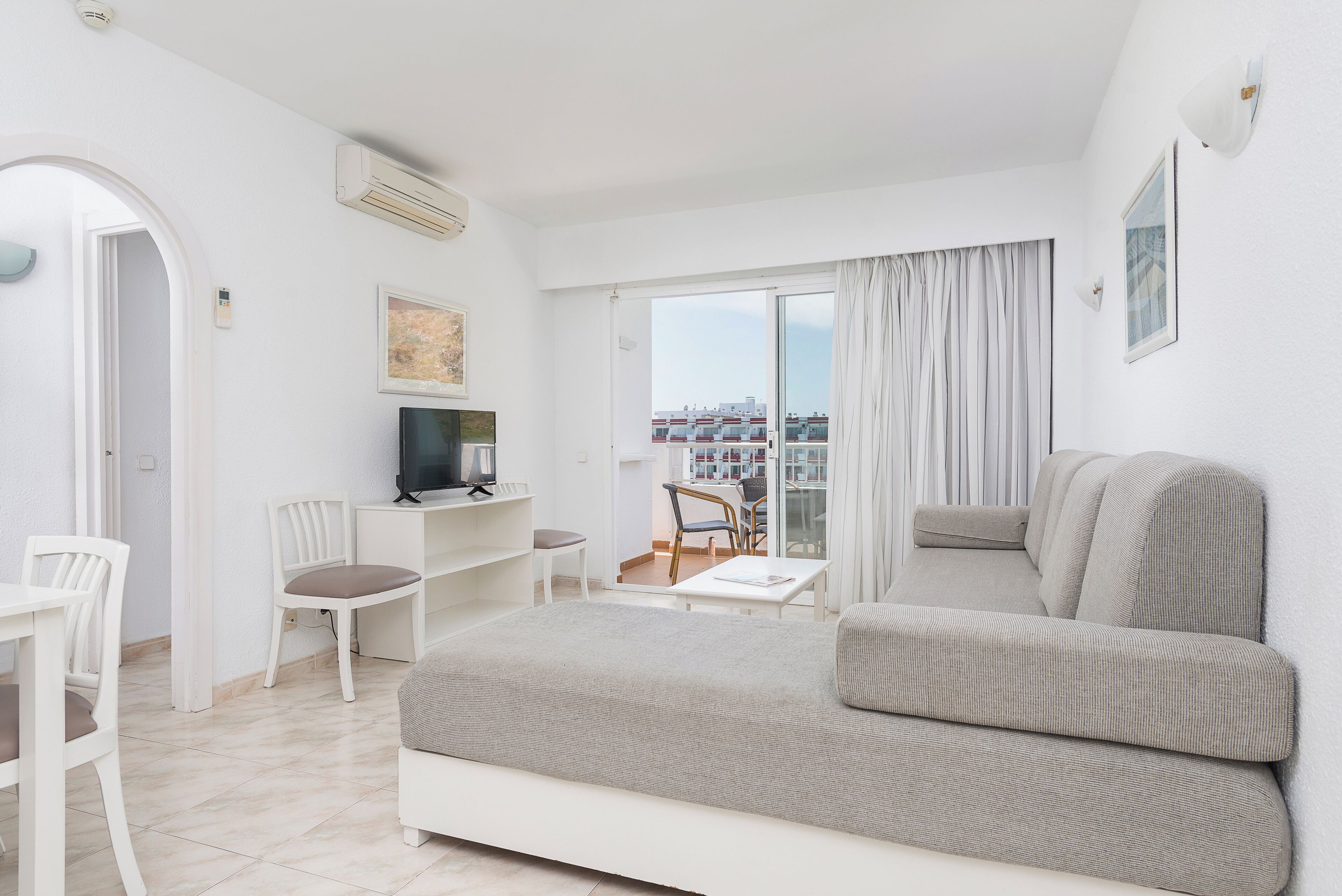 Ein modernes Hotelzimmer mit einem großen Bett, einem Schreibtisch mit Computer, einem Stuhl und einem Balkon mit Blick auf die Stadt.