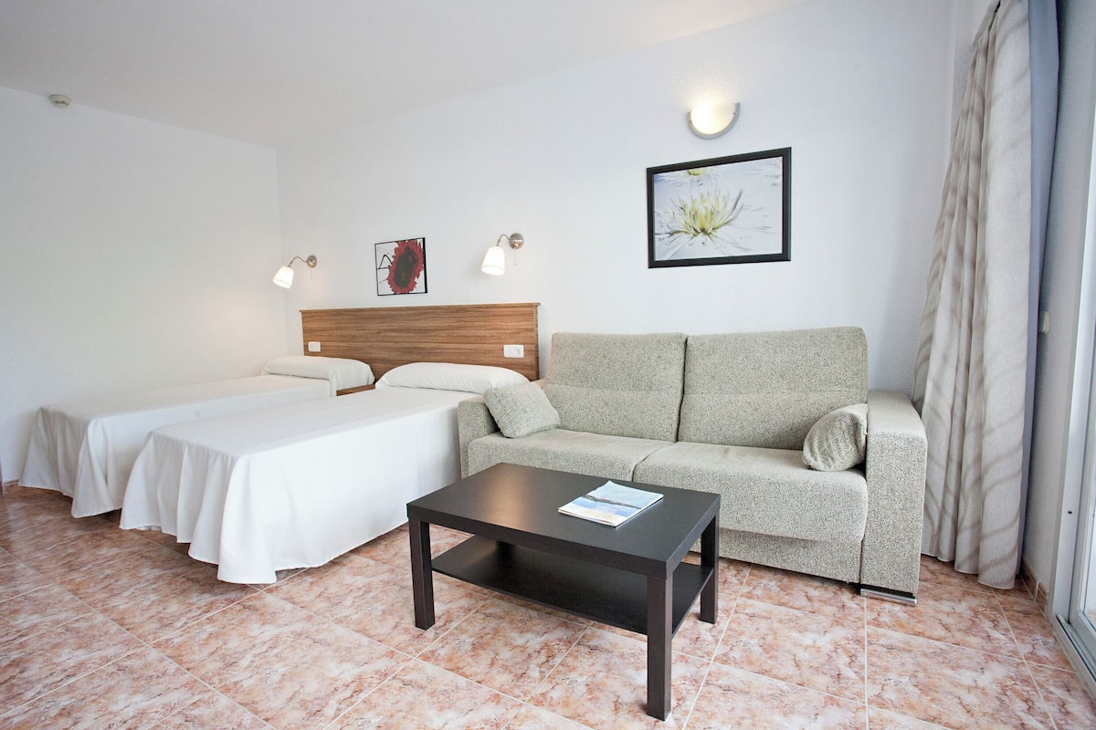 Ein Hotelzimmer mit Bett, Sofa, Couchtisch und einem Bild an der Wand.