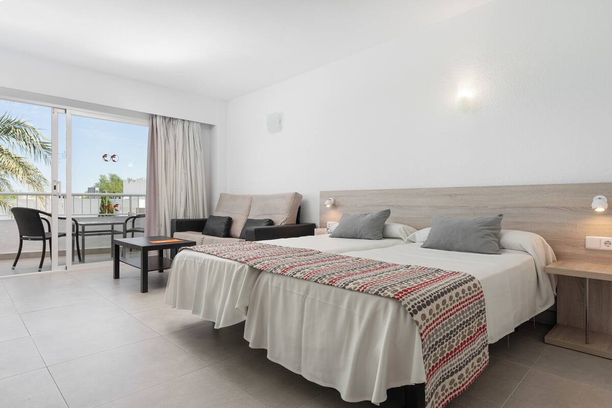Ein Hotelzimmer mit einem großen Bett, einem Schreibtisch, einem Stuhl und einem Balkon mit Blick.