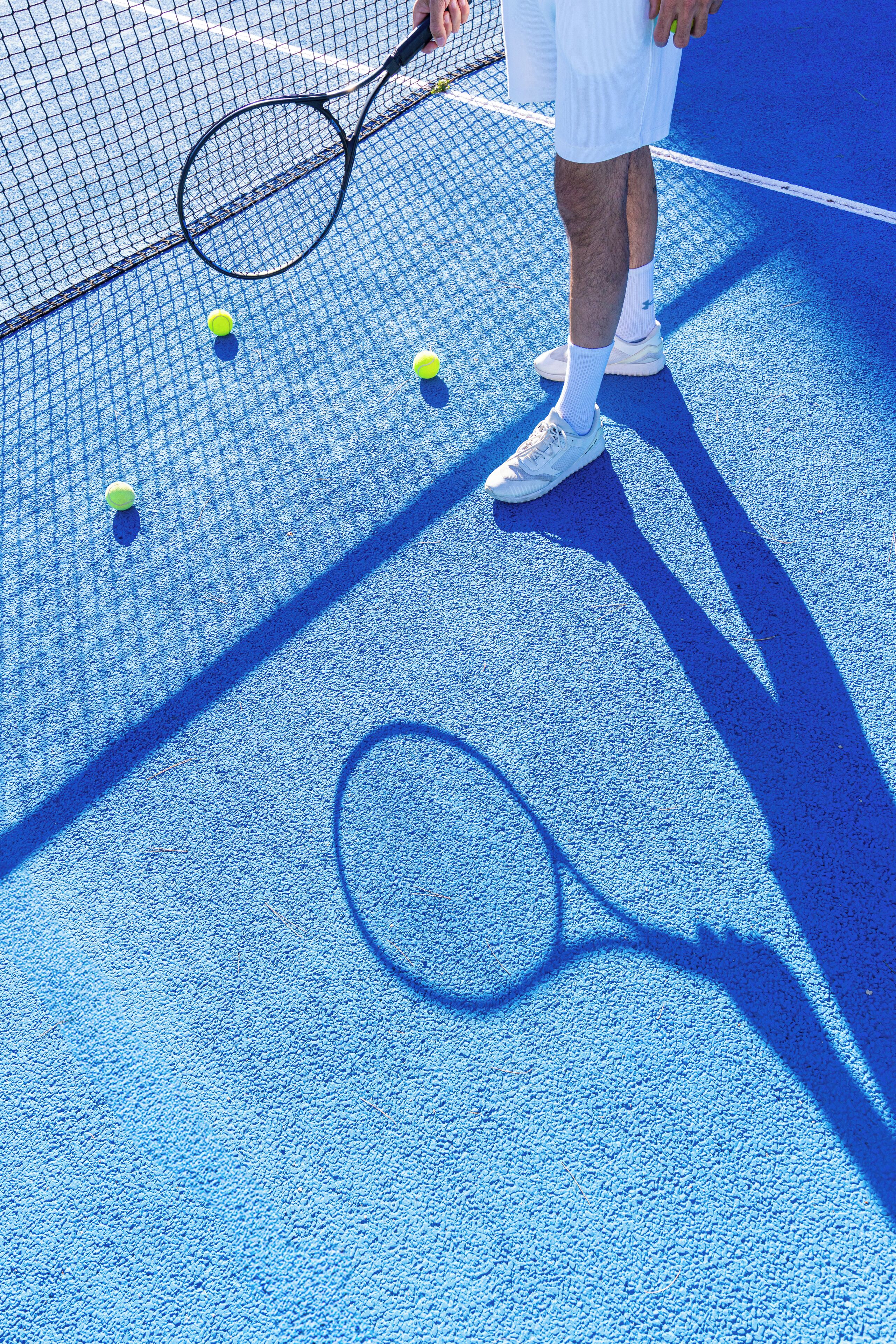 A close-up of a tennis court with a net, a tennis racket, and tennis balls.