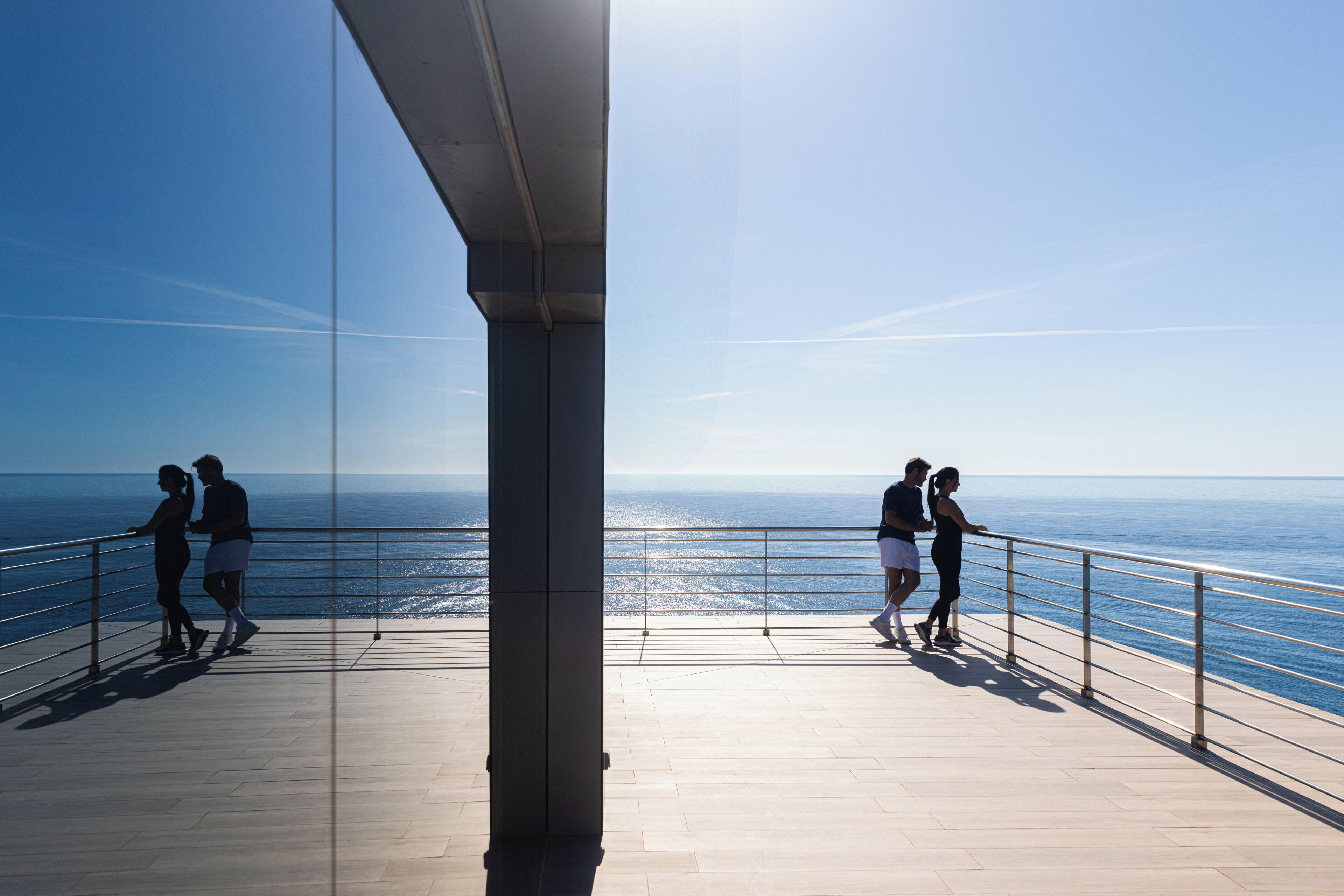 A balcony with a view of the ocean, a railing, and a clear sky.