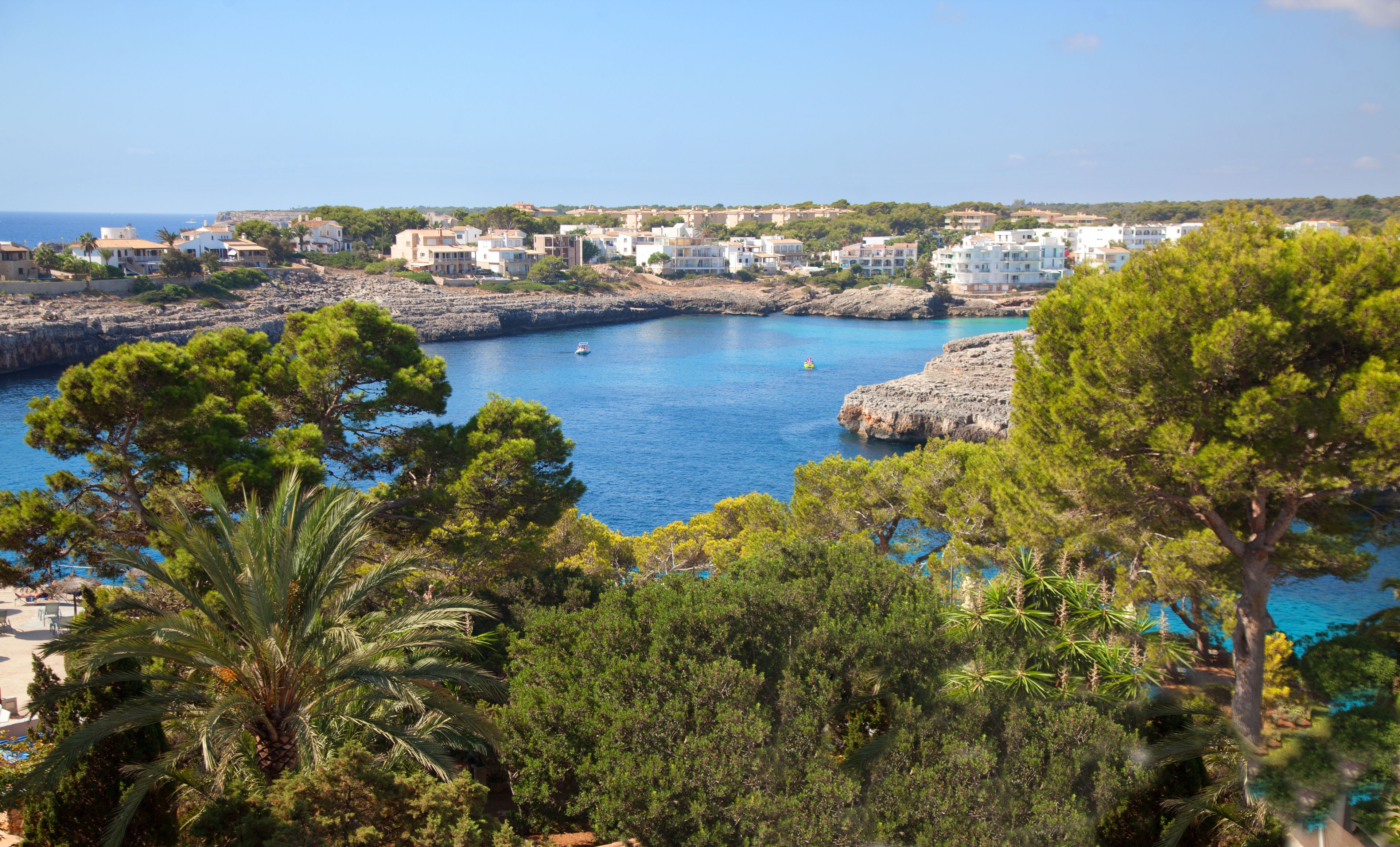 Un pueblo costero con edificios a lo largo de la costa, acantilados rocosos y abundante vegetación.