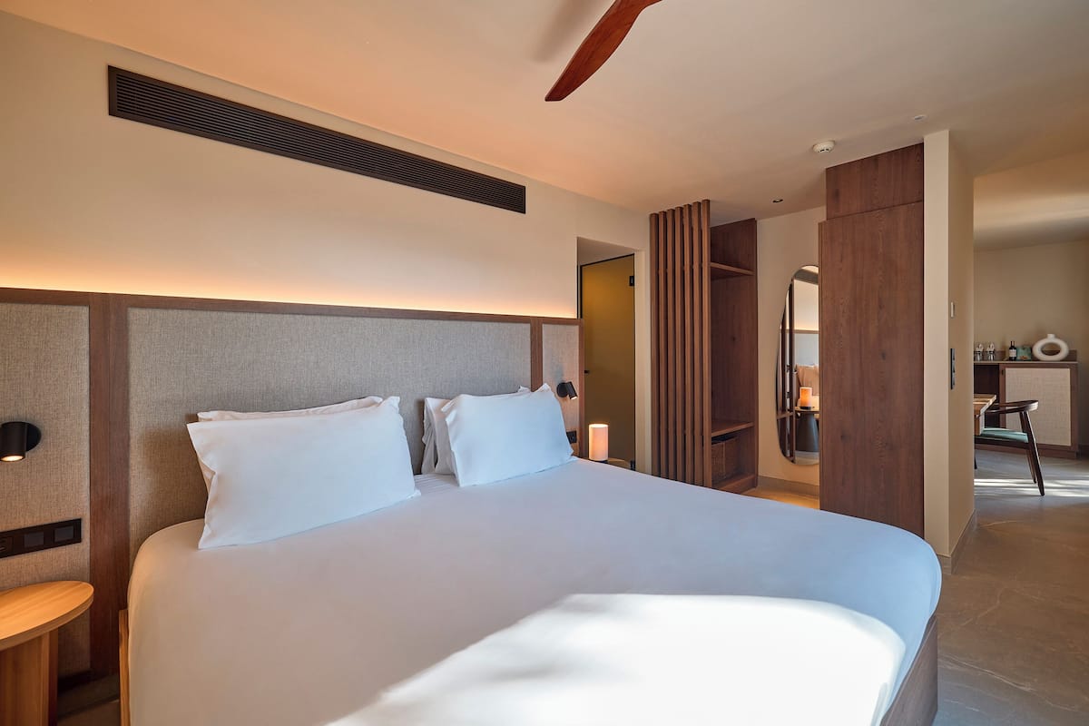 A modern hotel room with a large bed, bedside tables, a desk, and a wardrobe.