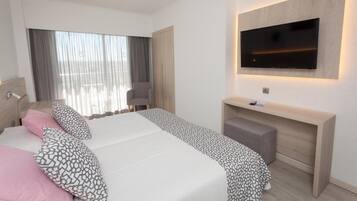 Una habitación de hotel moderna con una cama grande, un televisor montado en la pared, un escritorio y una silla.