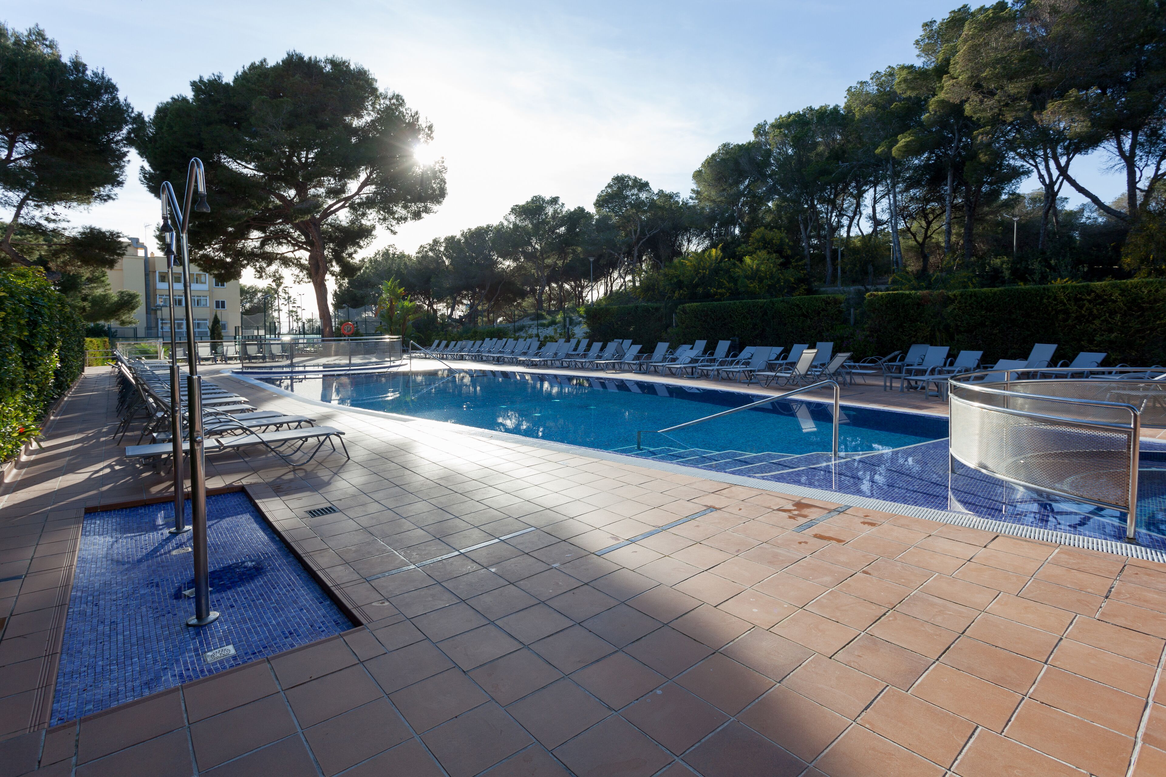 A swimming pool with tiled flooring and lounge chairs.