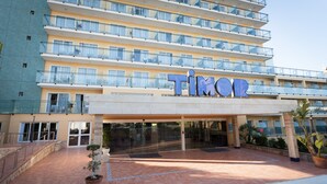 A multi-story hotel with a prominent 'TIMOR' sign, outdoor seating, and a tiled courtyard. - Hotel Timor (Palma de Mallorca)