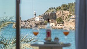 Une vue sur la côte, avec un phare, des bâtiments et une table sur laquelle sont posés deux verres.