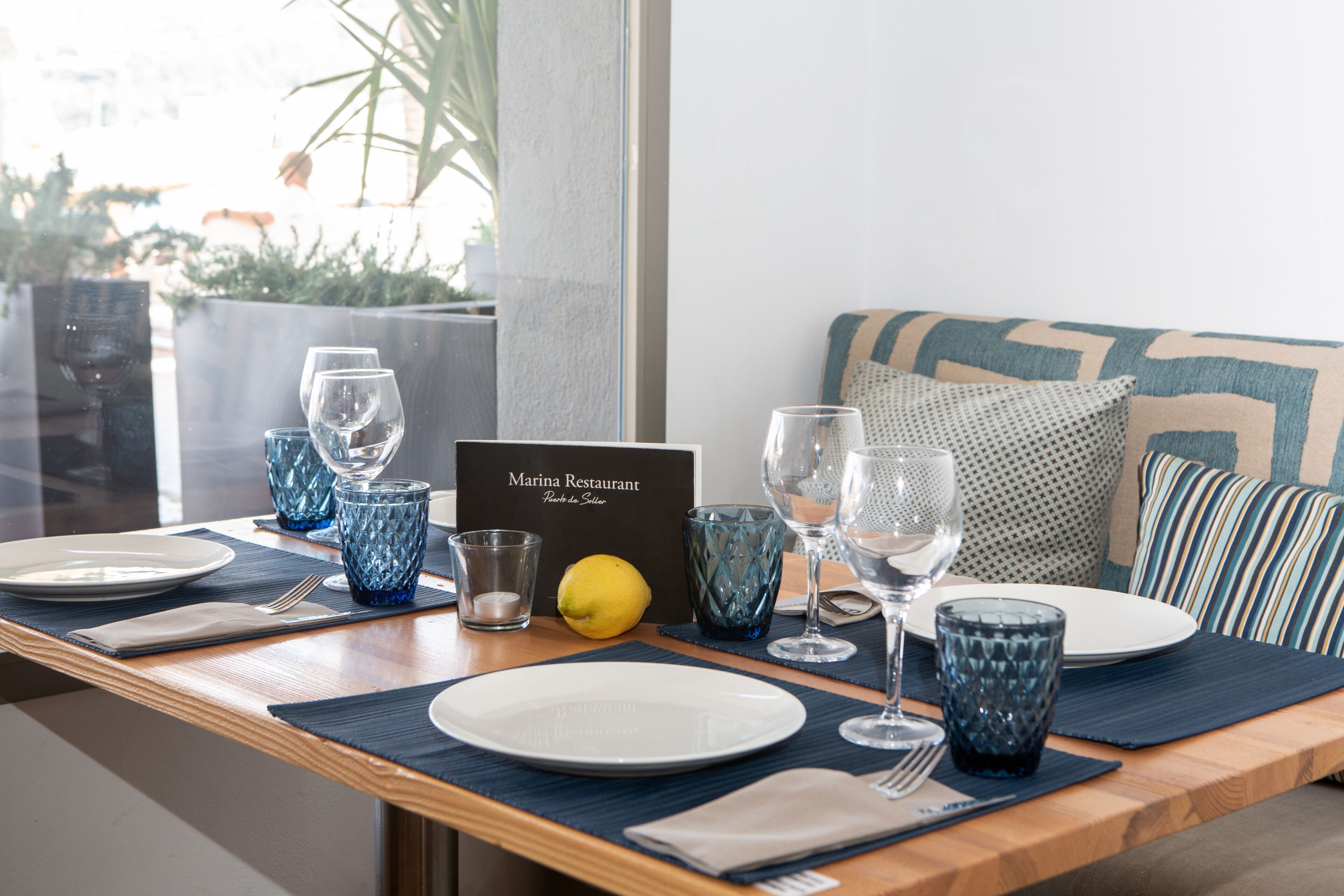 Une table dressée dans un restaurant, avec des assiettes, des verres et un menu.