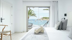Une chambre avec un lit, une chaise, une serviette et une vue sur la mer.