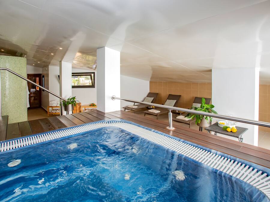 Un área de piscina interior moderna con vista despejada, sillas de descanso y una pequeña mesa con limones.