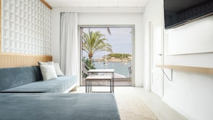 Une chambre moderne avec un canapé, une petite table et une vue sur un port de plaisance, visible à travers une porte vitrée.