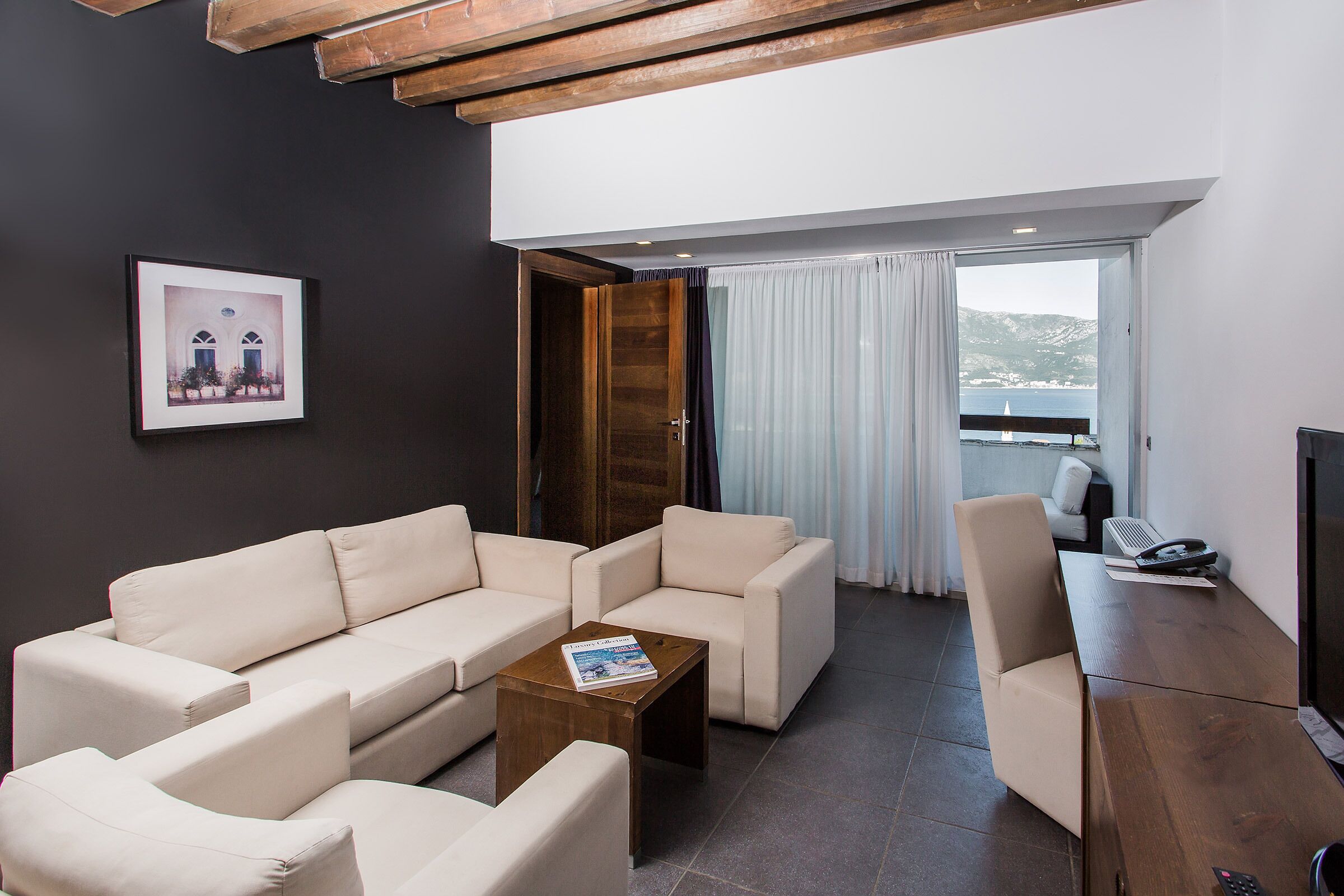 A modern living room with a sofa, armchairs, a coffee table, and a TV.