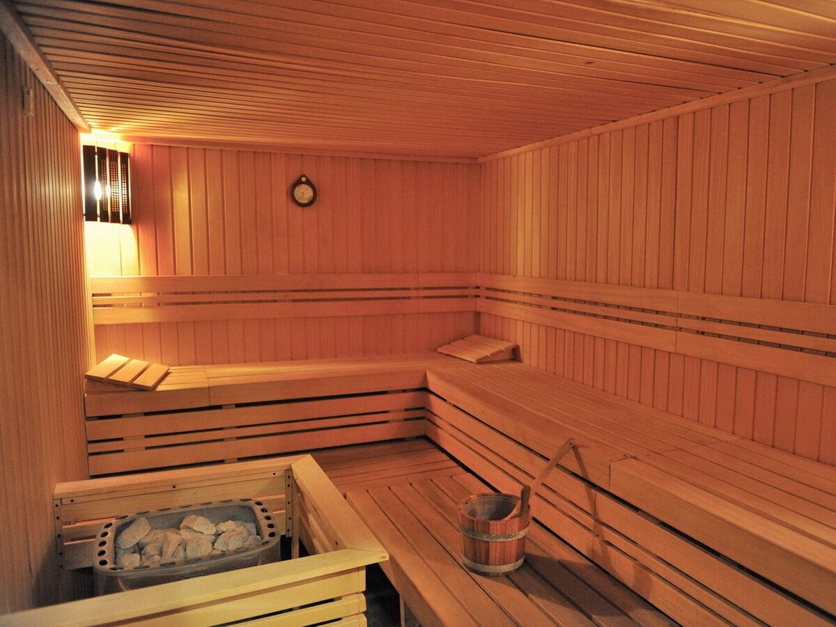 Una sauna con bancos de madera y un cubo de piedras.