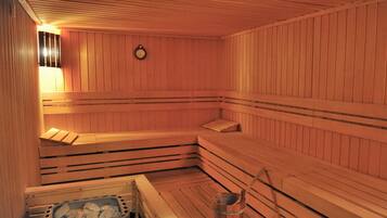 Una sauna con bancos de madera y un cubo de piedras.