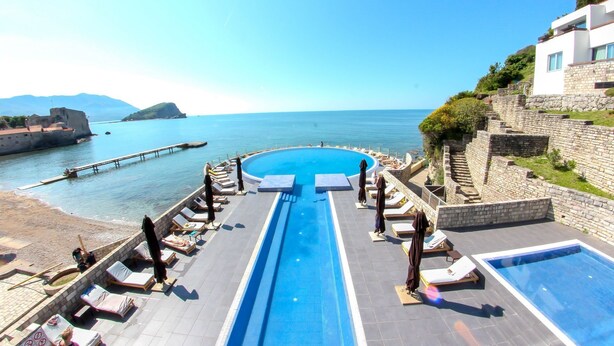 A pool area with lounge chairs and a view of the sea. - Avala Resort & Villas (Budva)