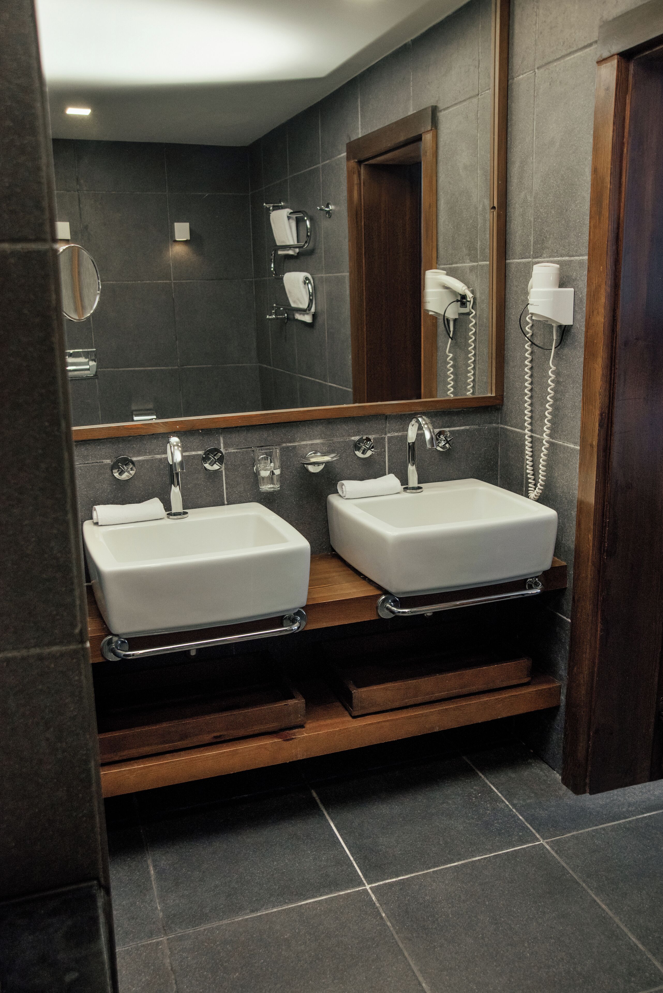 Une salle de bain moderne avec deux lavabos, un grand miroir et un meuble-lavabo en bois.