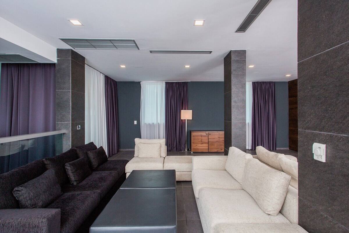 A modern living room with dark and light sofas, a coffee table, and a wooden cabinet.