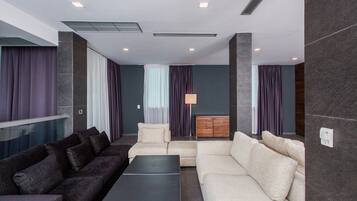 A modern living room with dark and light sofas, a coffee table, and a wooden cabinet.