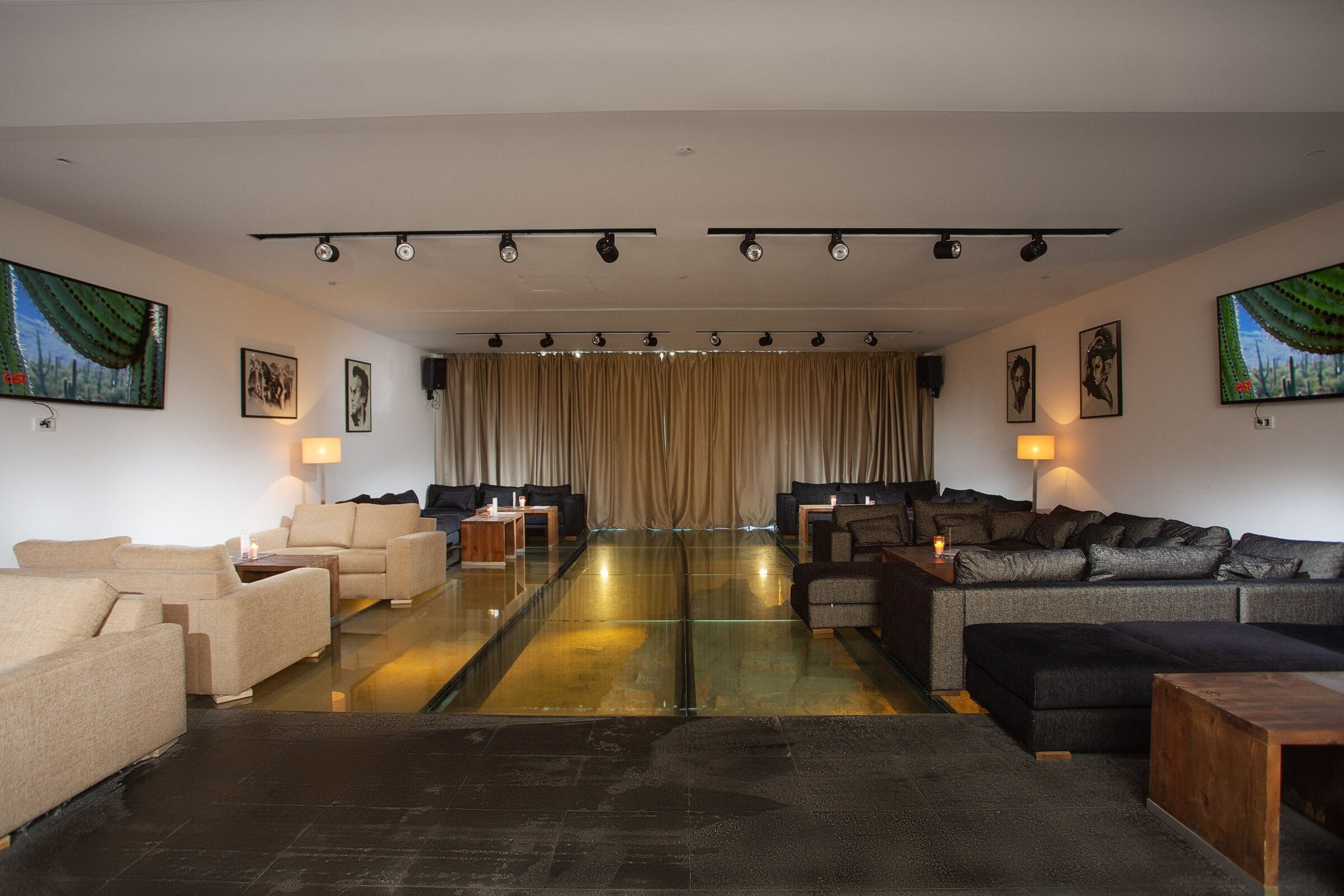 Amplia sala de estar con varios sofás y una mesa de centro de vidrio, con una paleta de colores neutros y decoración moderna.