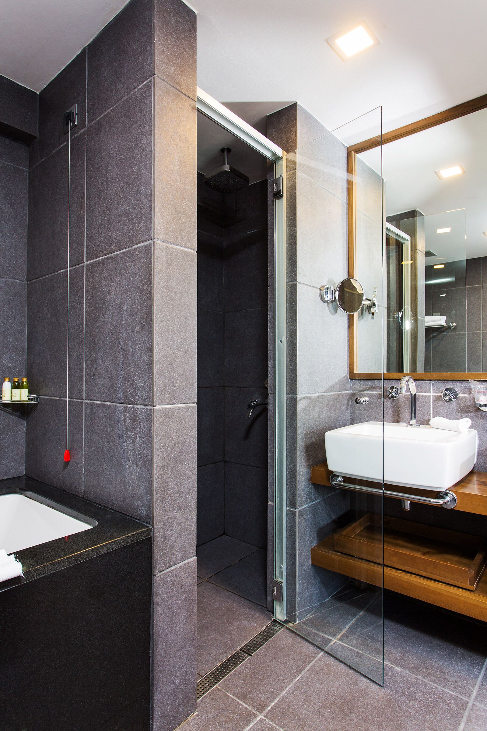 Un baño moderno con ducha de vidrio, un lavamanos blanco y un espejo grande.