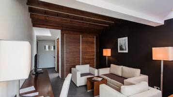 Un salon moderne avec un plafond en bois, des canapés blancs, une table basse et un téléviseur.