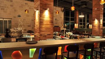 A bar area with a long counter, multiple stools, and a variety of bottles and glasses.