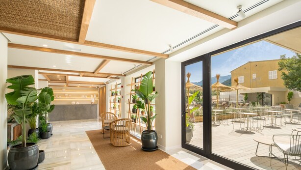 Un moderno vestíbulo de hotel con un amplio ventanal que da a una zona de estar exterior.