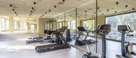 Une salle de sport équipée de tapis de course, de vélos d’appartement et d’appareils de musculation.