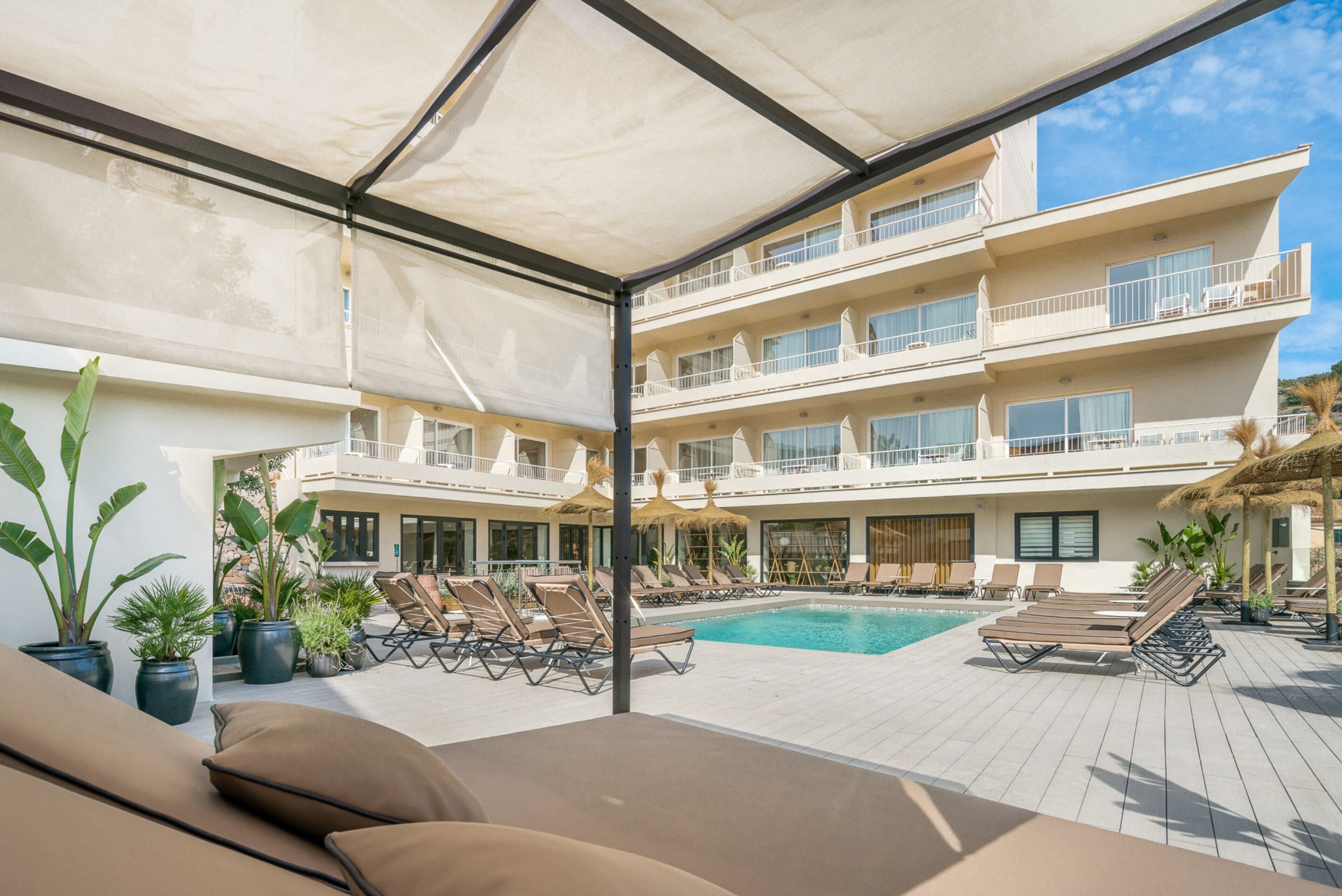 A rooftop pool area with lounge chairs and potted plants.