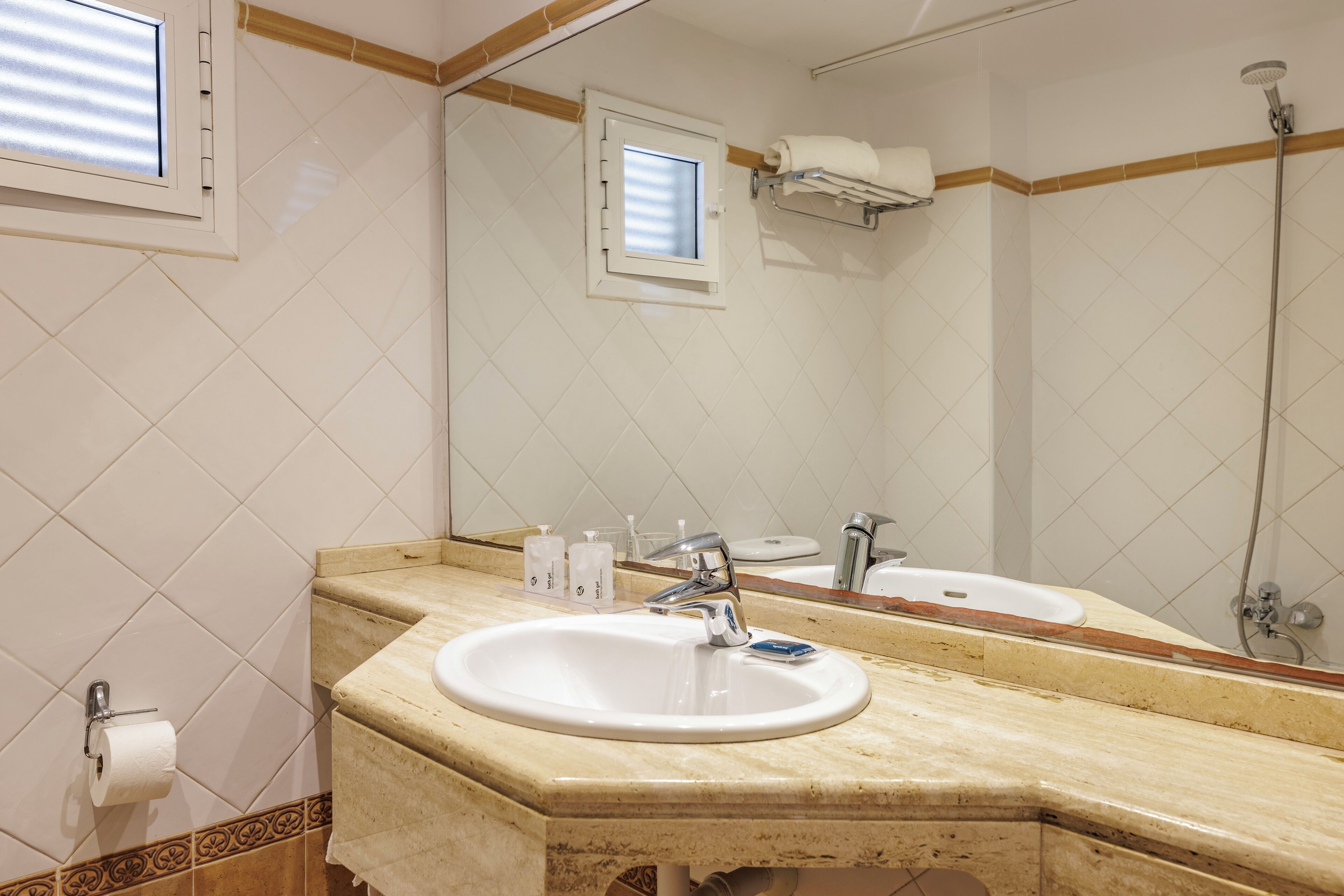 A bathroom with a sink, mirror, and shower.