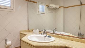 Un baño con lavabo, espejo y ducha.