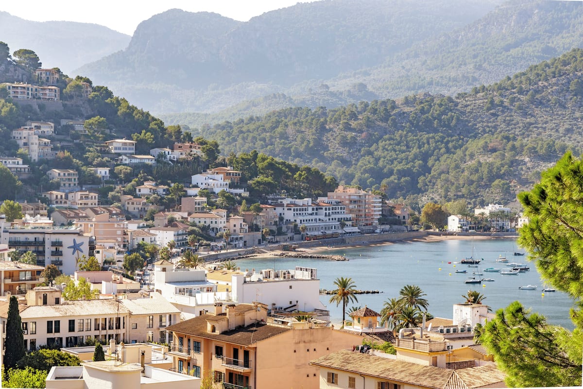 A coastal town with buildings on a hillside overlooking a bay with boats.