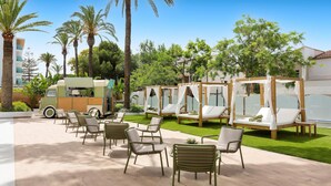 Un resort con mesas al aire libre, palmeras y un camión de comida.