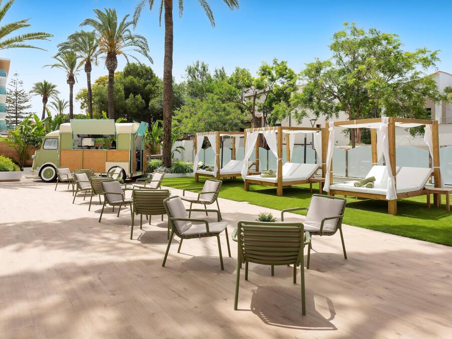 A resort with outdoor seating, palm trees, and a food truck.