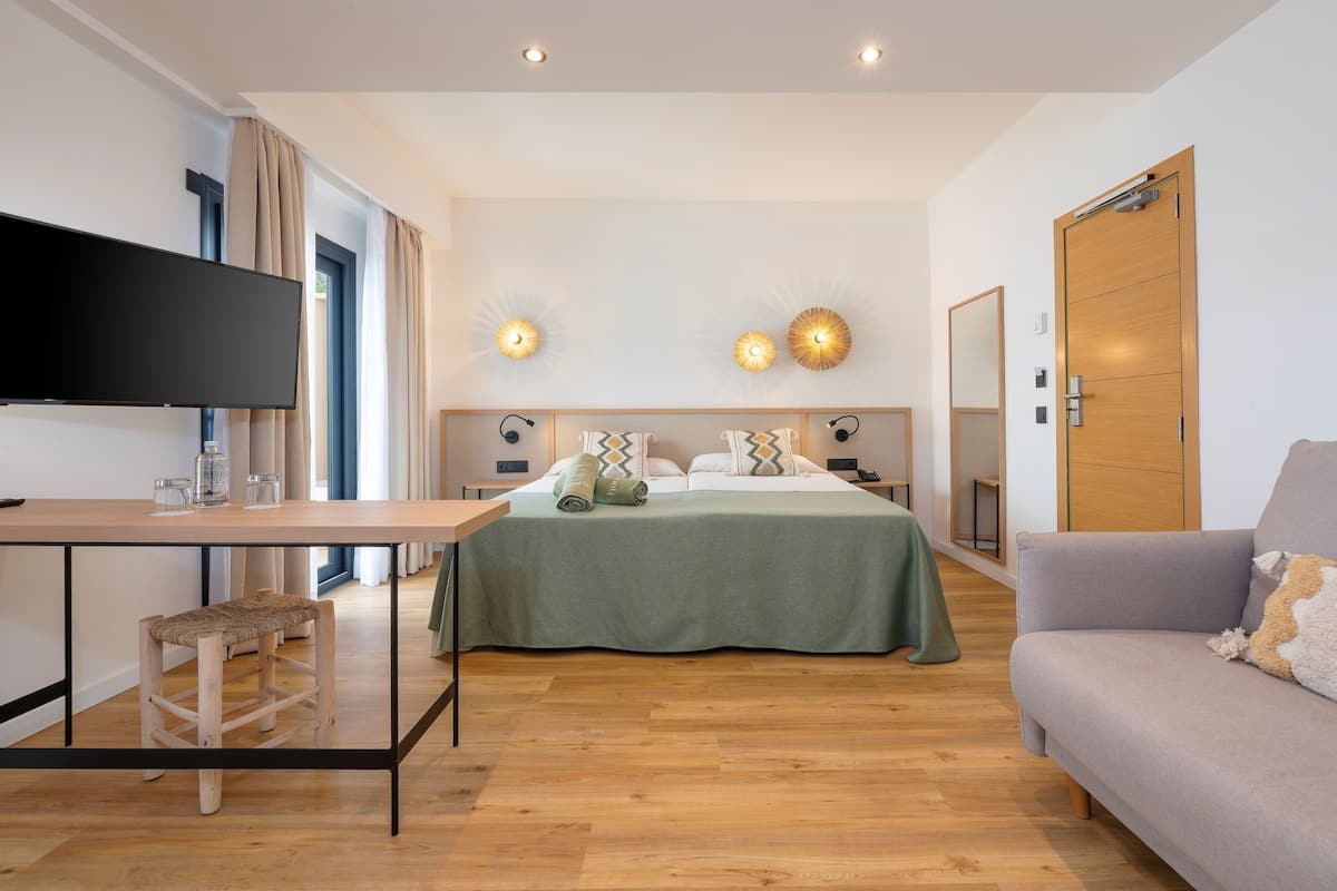 Een moderne hotelkamer met een bed, een sofa, een televisie en een bureau.