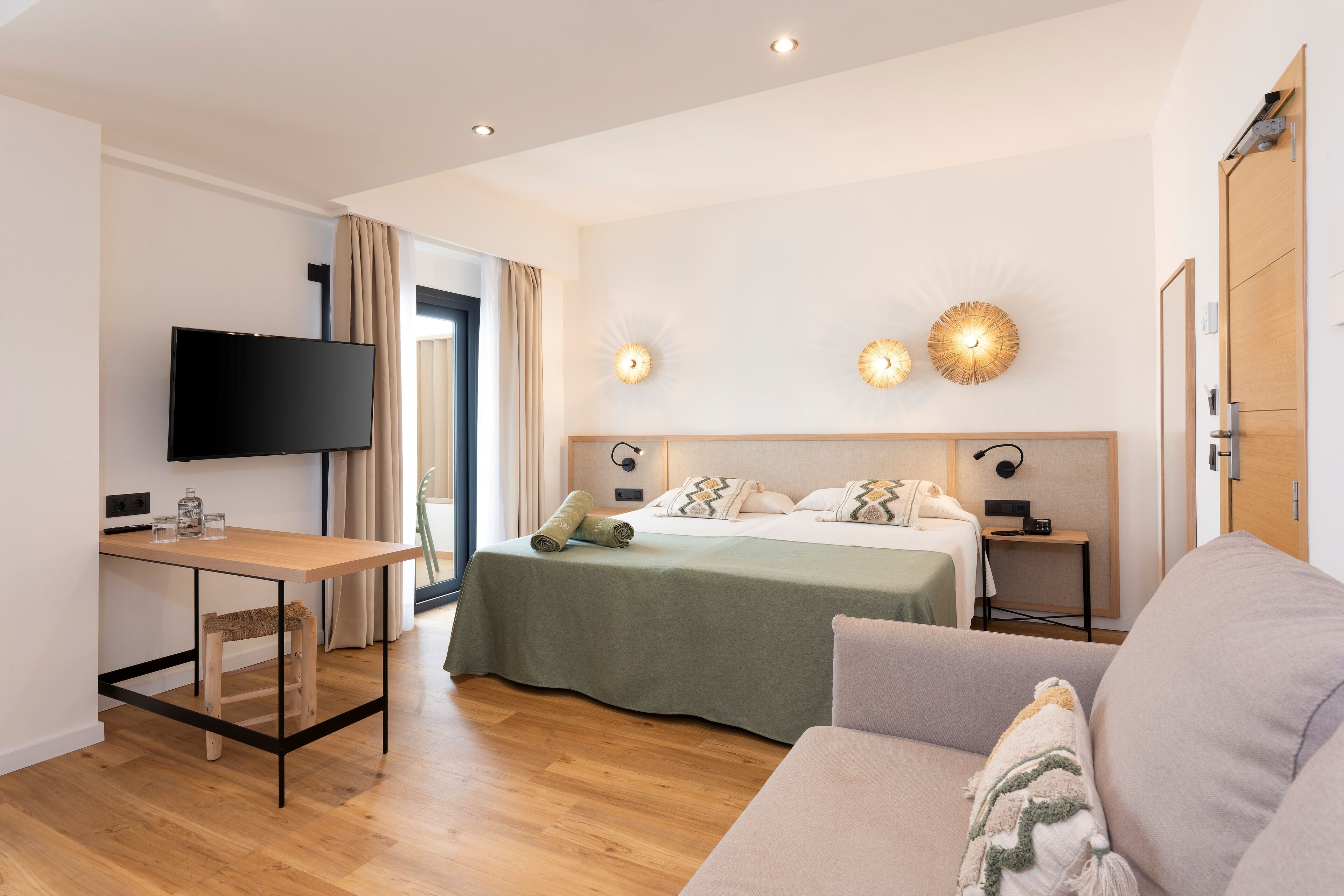 Een moderne hotelkamer met een bed, televisie, bureau en een bank.