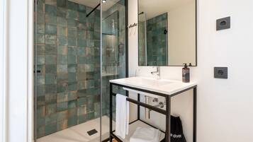 Une salle de bain moderne avec une douche à parois de verre, un lavabo blanc et un grand miroir.