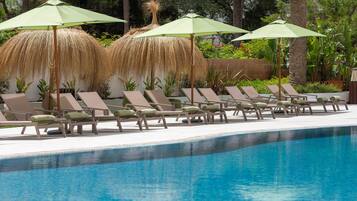 A poolside area with lounge chairs and thatched umbrellas.