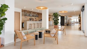 Un vestíbulo amplio con mobiliario de madera, una zona de bar y ventanas grandes.