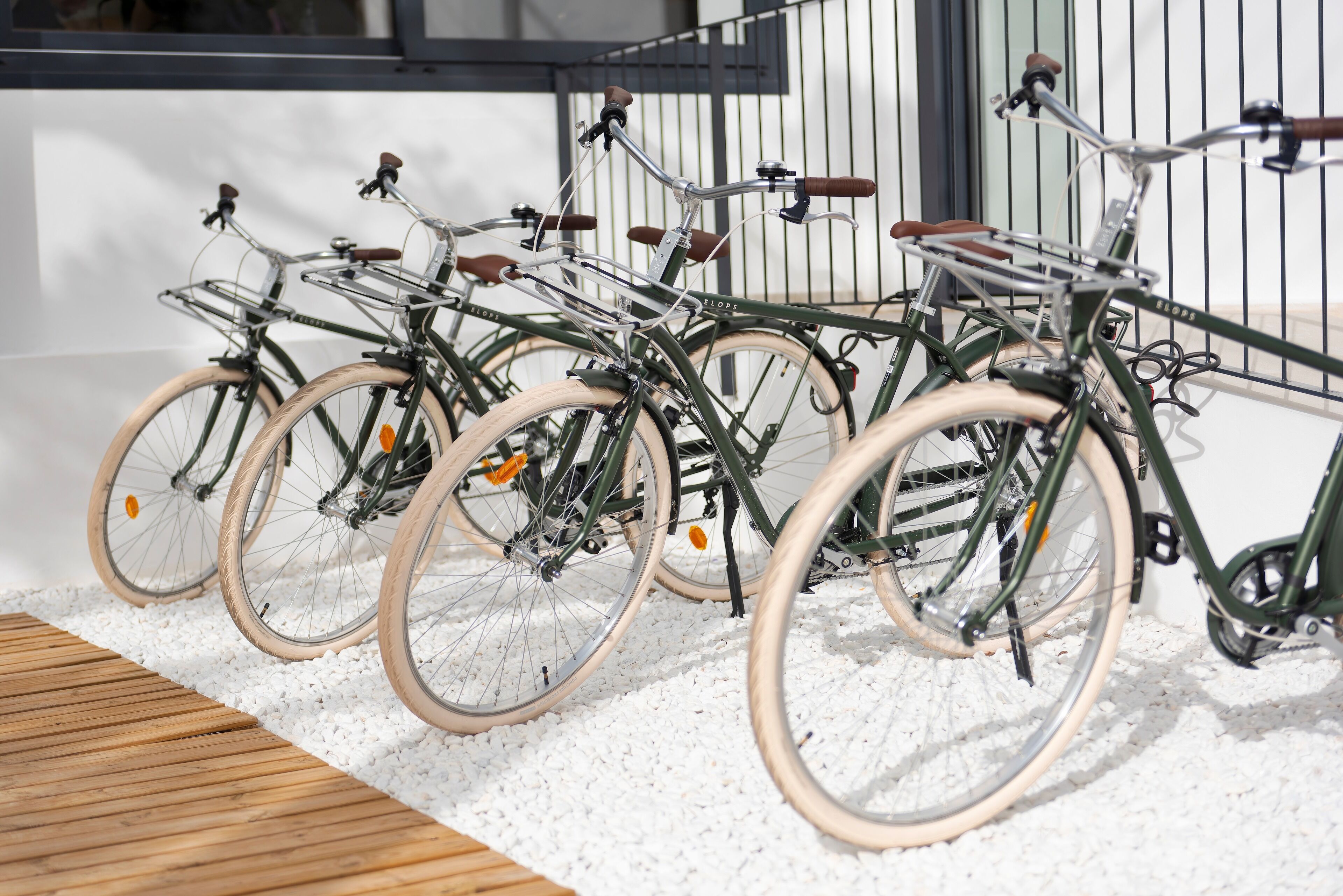 A row of bicycles parked against a wall with a wooden deck in front.