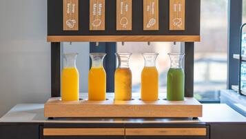 Un bar de zumos con etiquetas de madera para distintos jugos de fruta y cinco botellas de vidrio con jugo.