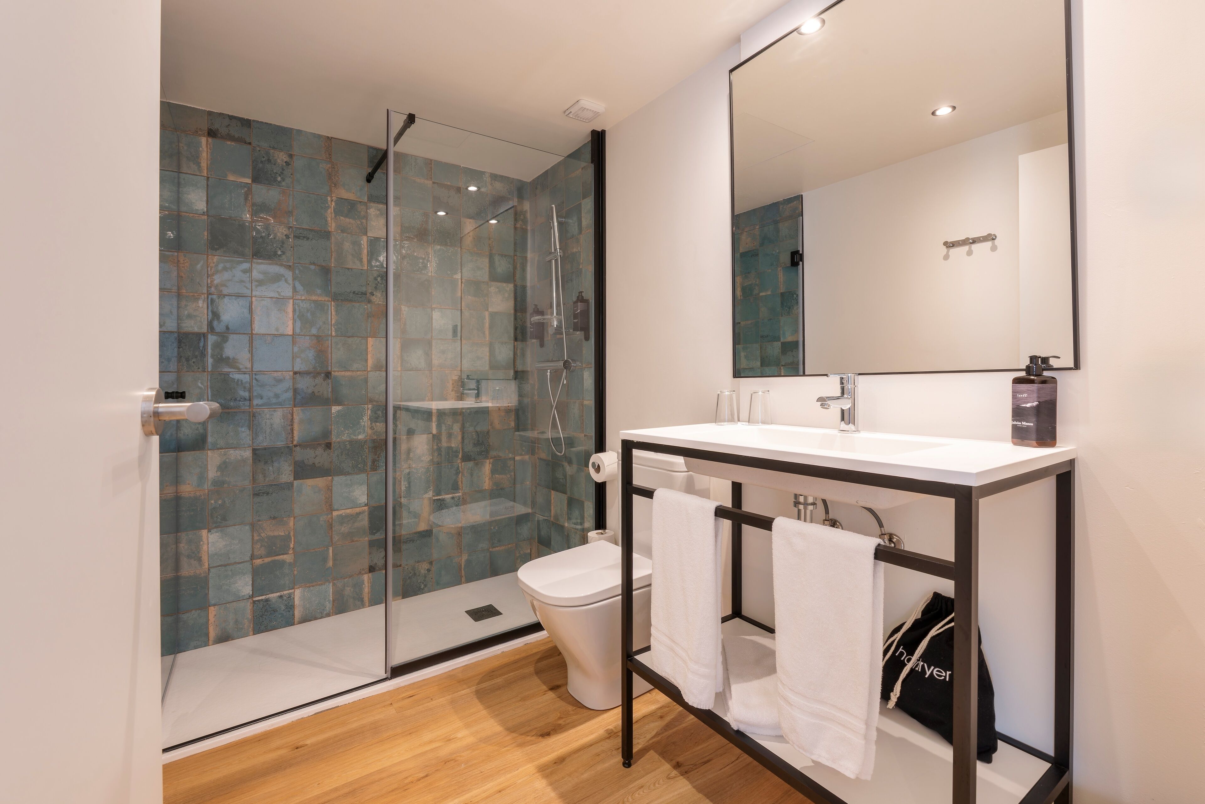 Un baño moderno con cabina de ducha de vidrio, un lavabo blanco y un espejo grande.