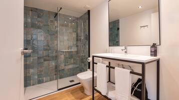 Un baño moderno con cabina de ducha de vidrio, un lavabo blanco y un espejo grande.