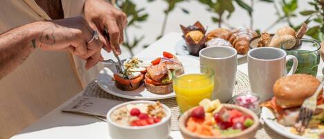 Een ontbijttafel met croissants, gebak, fruit en koffie.
