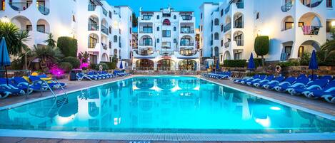 Una piscina al aire libre, sillones reclinables de piscina