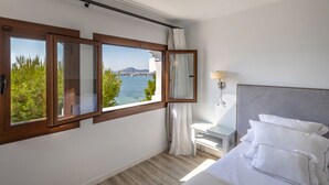 A bedroom with a large window, a bed, a bedside table, and a nightstand. - Hoposa Bahía (Pollenca)